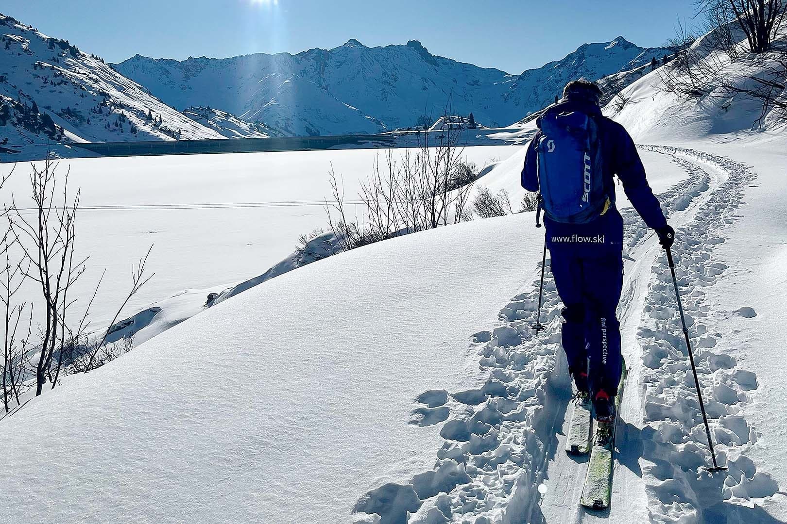 Eine Person auf Skitour im Aufstieg über einen stillen Hang im Morgenlicht.