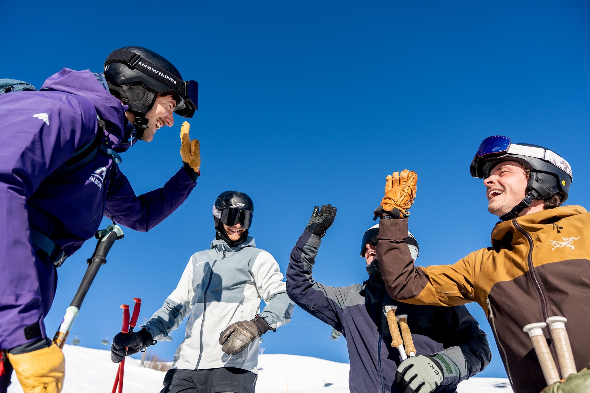 Vier flow Guides klatschen sich unter tiefblauem Arlberg-Himmel ab.